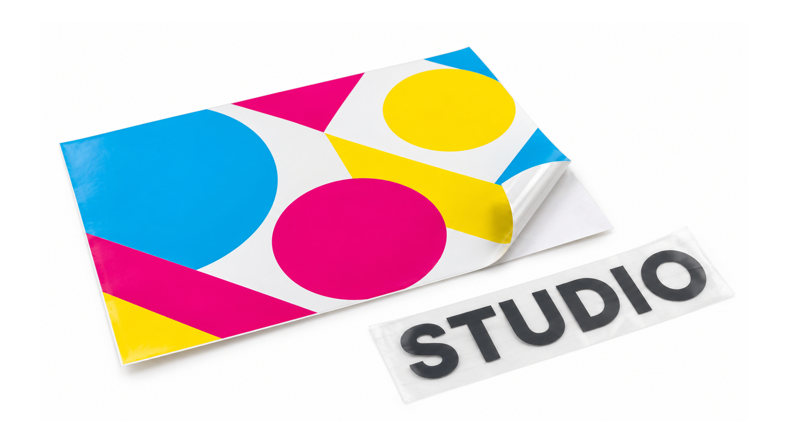 Bedruckte Klebefolie mit abgelöster Ecke neben Klebebuchstaben STUDIO auf Transferfolie