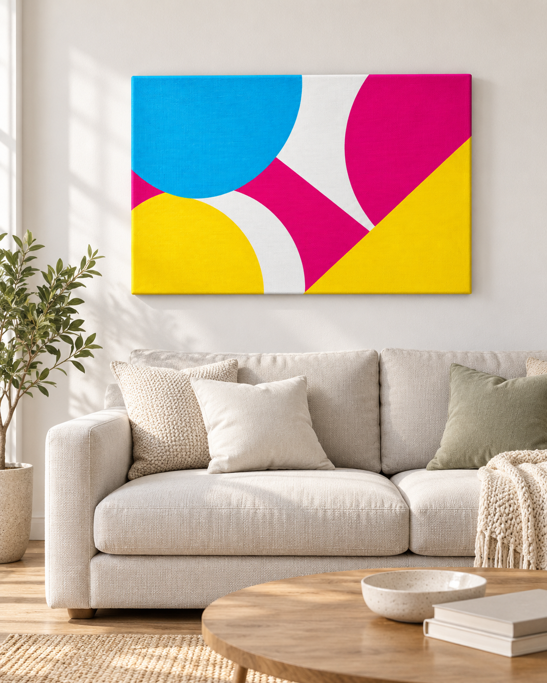 Leinwandbild mit geometrischem CMY-Motiv an einer hellen Wohnzimmerwand über einem Sofa
